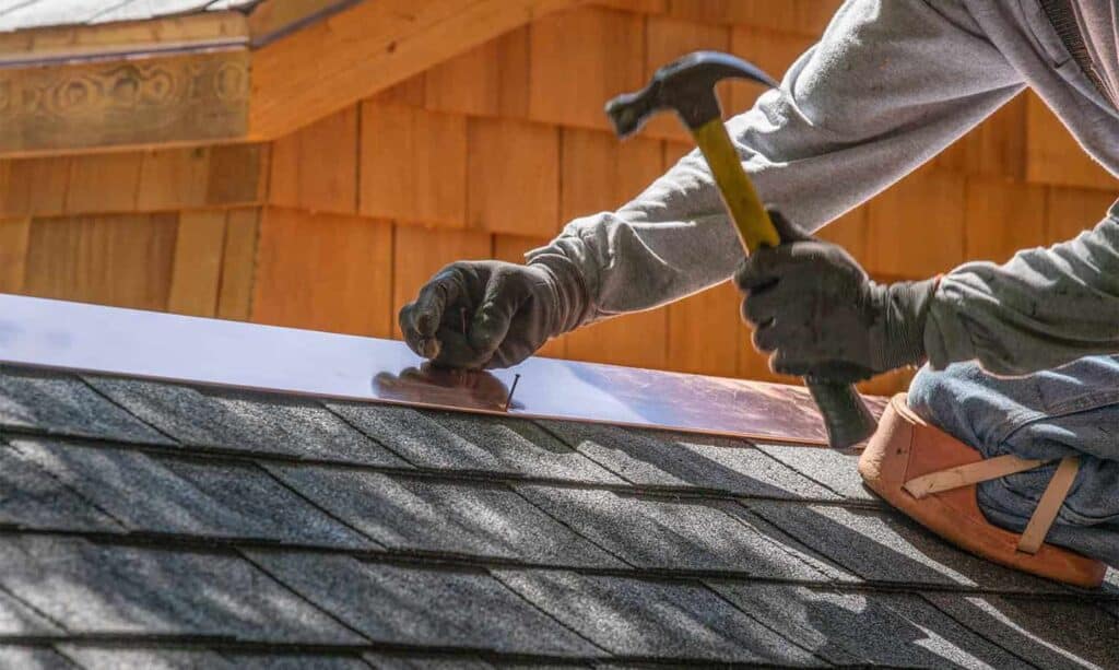 carpenter installing metal sheets to roof