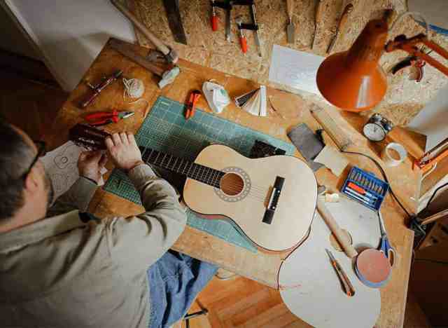 Man fixing guitar in garage workshop