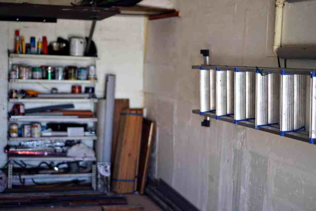 Ladder hanging on hooks in organized garage. 