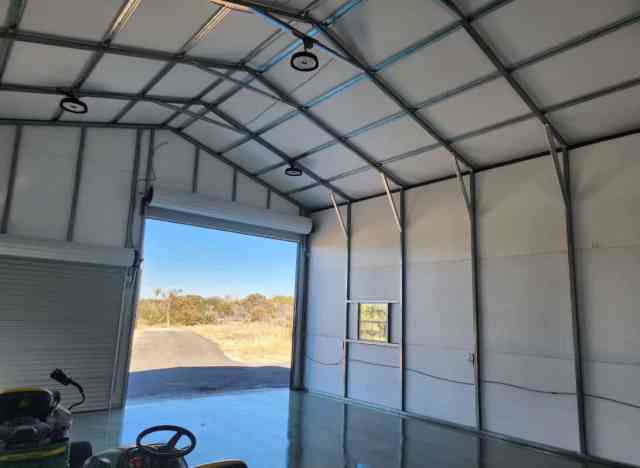 Interior of a metal building from Alan's Factory Outlet with the roll door open and a dirt road just outside