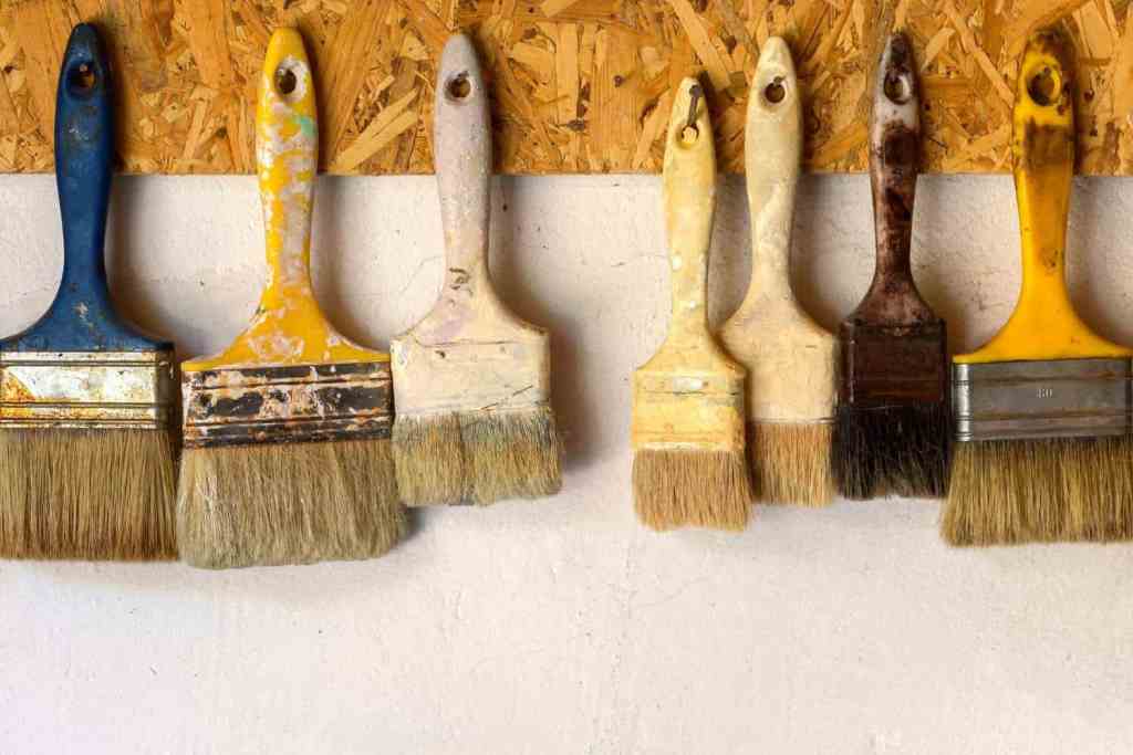 Paint brushes hanging on garage wall.