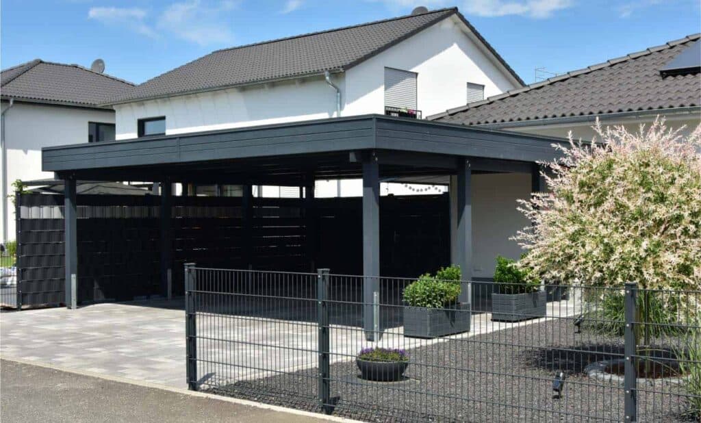 A carport attached to a white house with a gray roof.