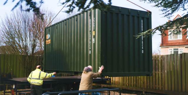 Shipping container being delivered and positioned on a residential property