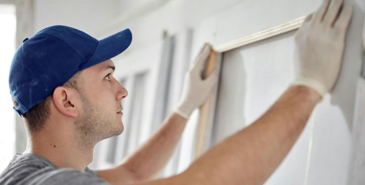 Worker installing trim on an interior wall using a level