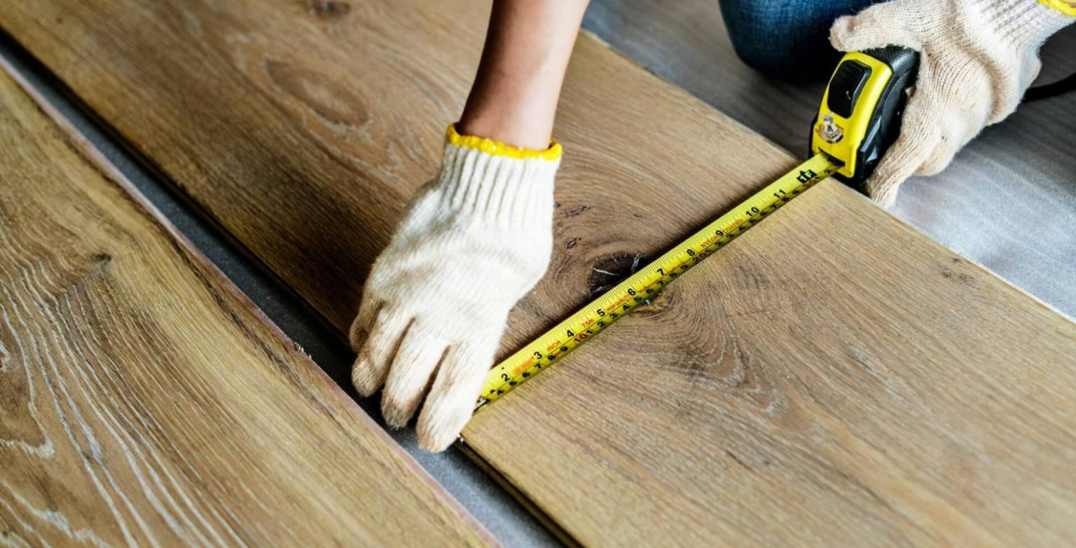 Measuring wooden floor planks with a tape measure