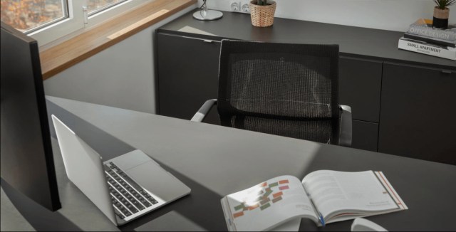 Modern office setup with a laptop, books, and a black chair