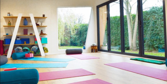 Yoga studio with bright natural light, colorful mats, and large windows