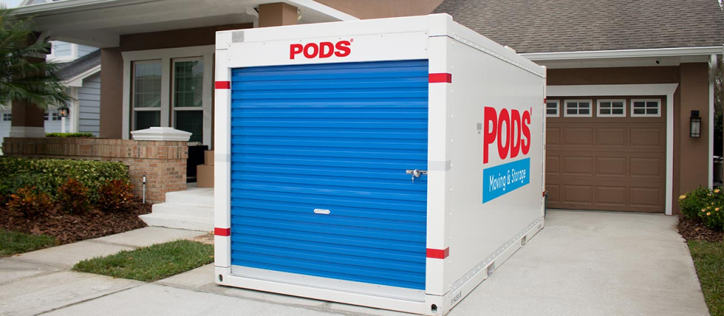 A curbside storage pod resting on the a large house's driveway