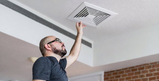 Homeowner adjusting a ceiling air vent for improved ventilation