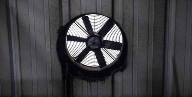 Industrial exhaust fan mounted on a metal wall for garage ventilation