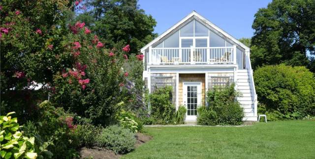 Detached garage addition with upper-level living space, balcony railing, and garden landscaping
