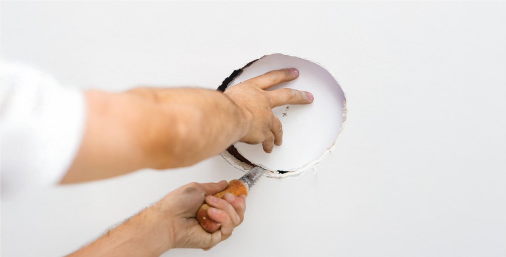 Hand cutting a hole in drywall