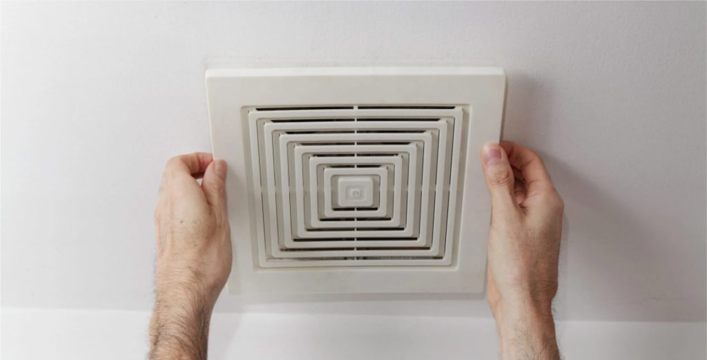 Hands installing a ceiling vent cover