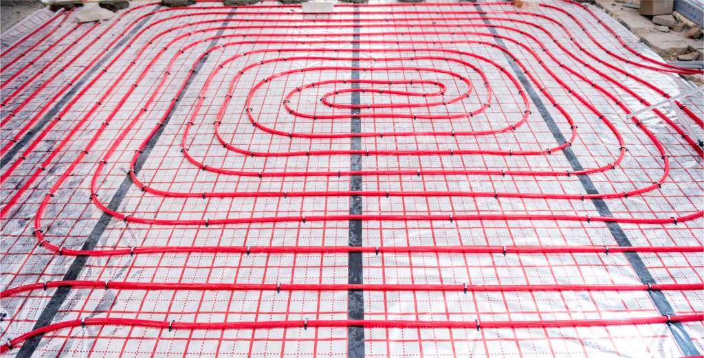 Red tubing for underfloor heating installation on a prepared surface