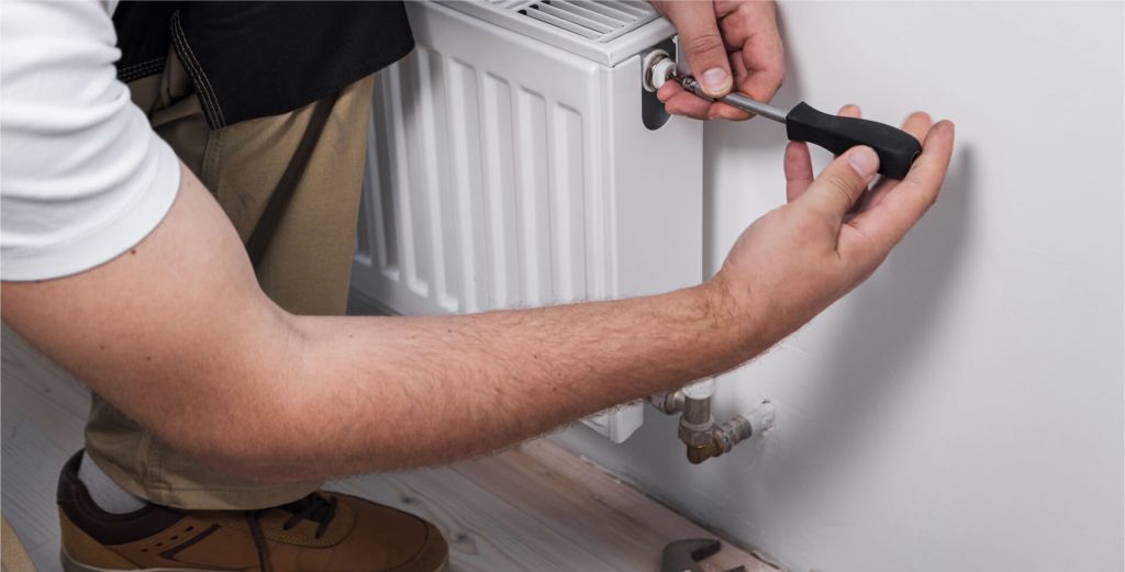 Technician adjusting a radiator valve with a screwdriver