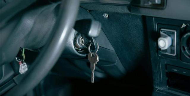 Car key inserted in the ignition inside a vehicle, showing dashboard and steering wheel detail