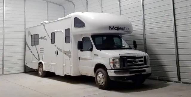 A white RV parked inside a large metal RV garage