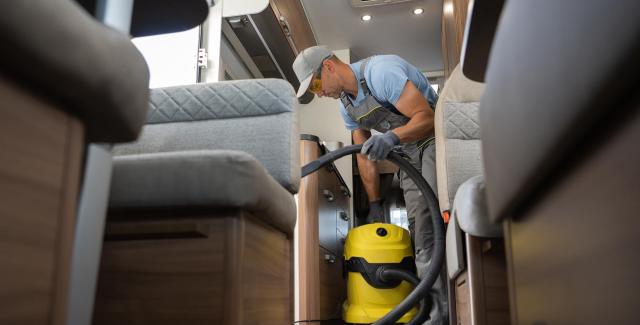 How to protect your RV from pests? A man vacuum cleaning the inside of an RV