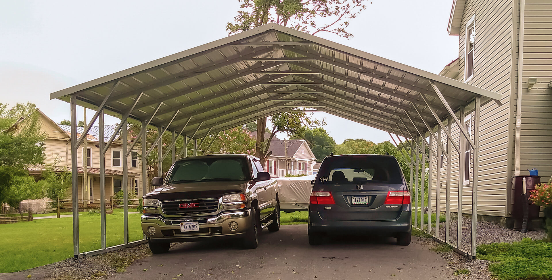 Side-by-side and trailer parked under a metal carport with boxed eave roof