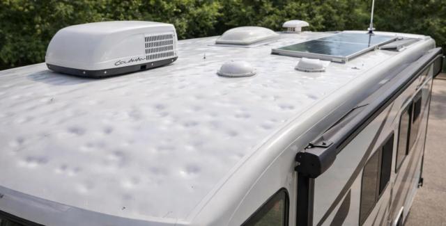 Top view of an RV roof showing air conditioning unit, solar panel, vents, and roof accessories