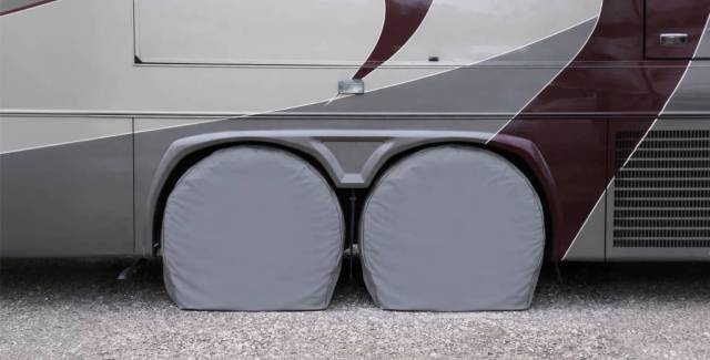 RV wheels protected with gray tire covers while parked on gravel