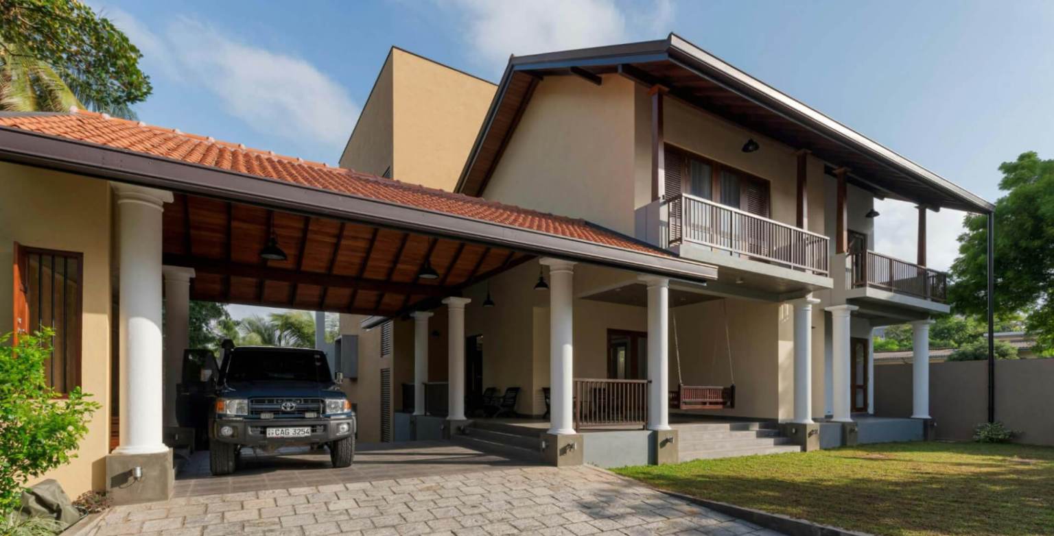 Covered carport attached to a two-story house with a vehicle parked underneath