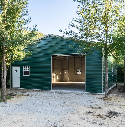 Green metal building with an open garage door