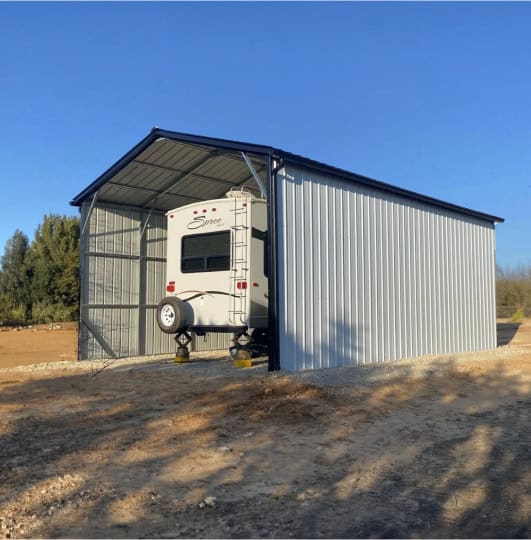 Large RV inside of a carport with closed sides