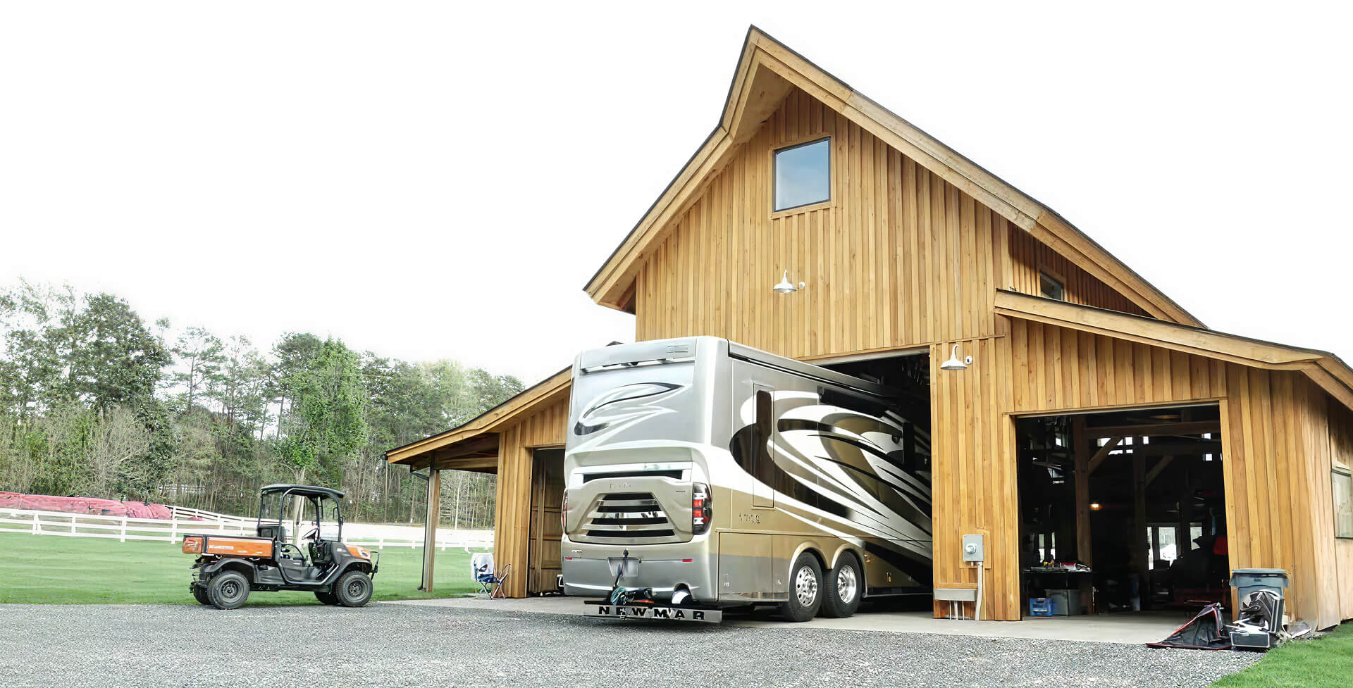 Wooden barn-style garage with motorhome and rural setting