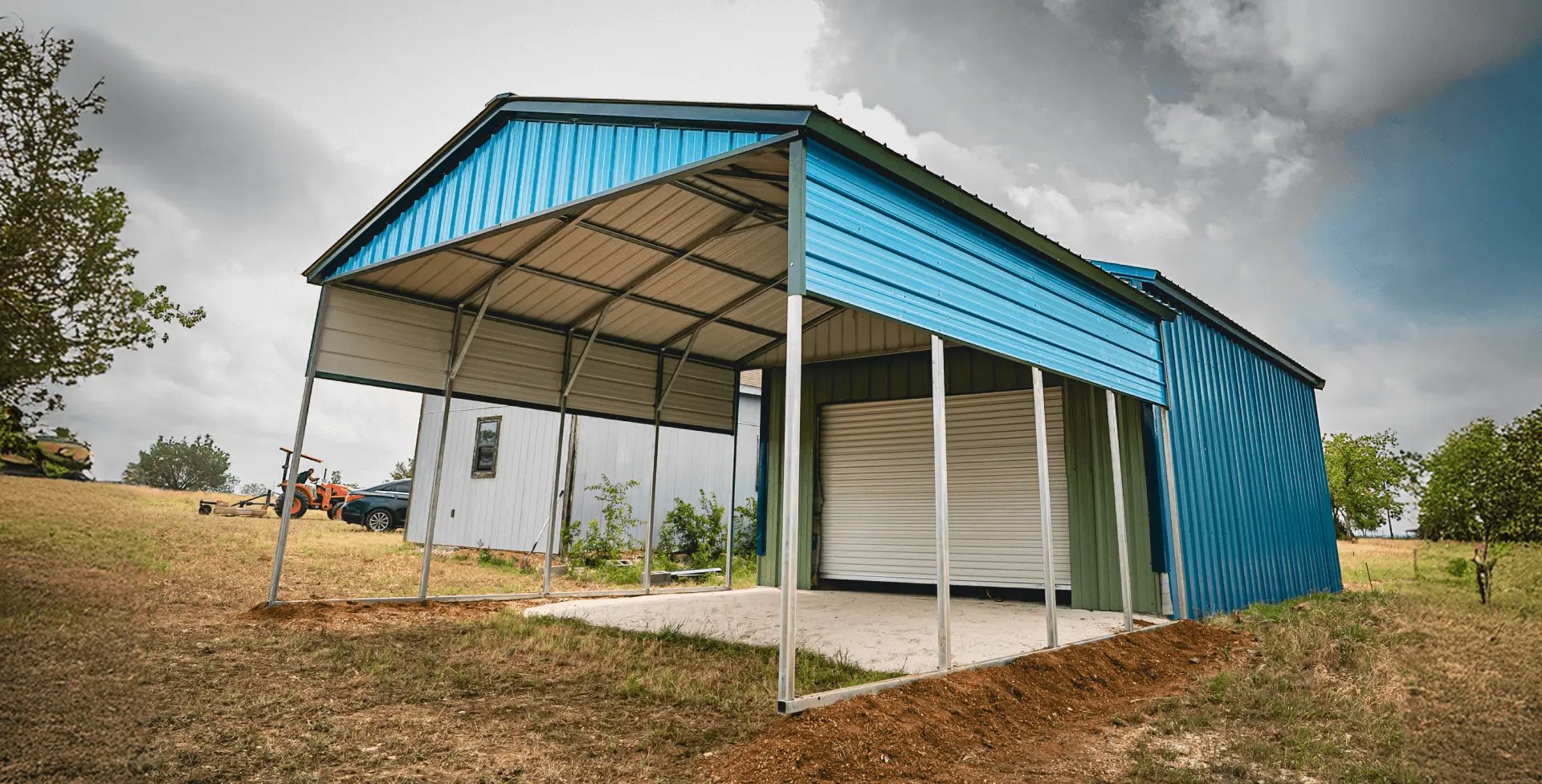 Blue steel carport and garage combo building with roll-up door on a concrete pad