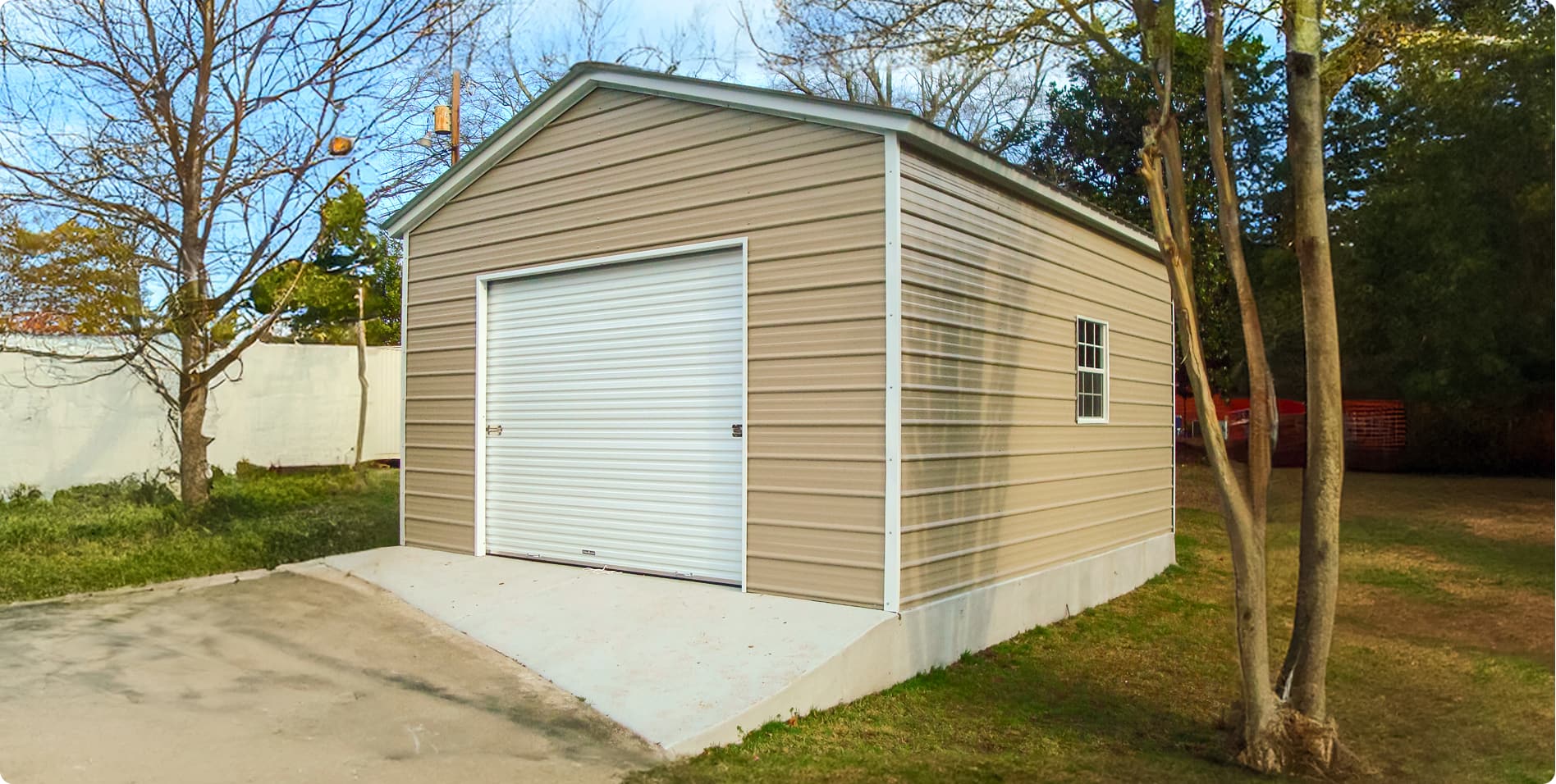 A tan single-car metal garage with a white roll-up door, built on a concrete slab in a backyard with trees, illustrating a compact and affordable metal garage option.