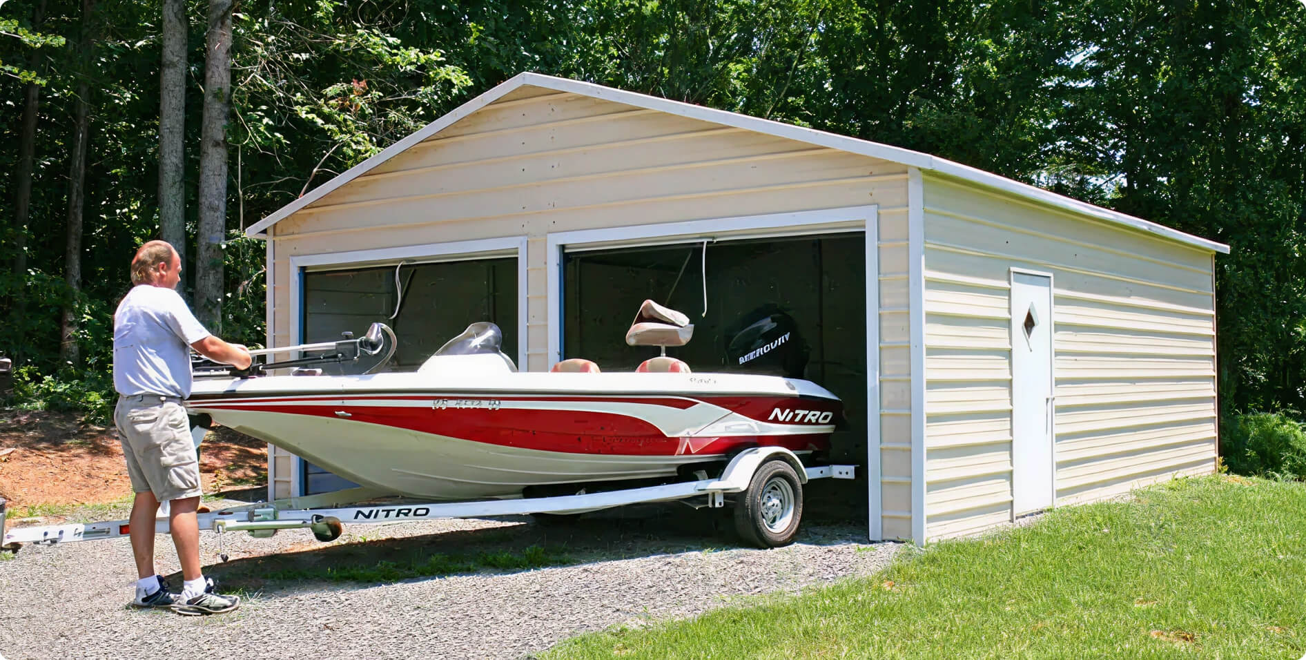 A man stores a red and white fishing boat inside a metal garage with two open roll-up doors.