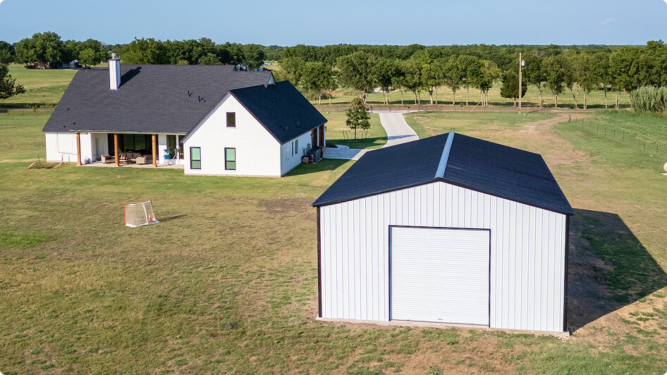 House and metal garage in field