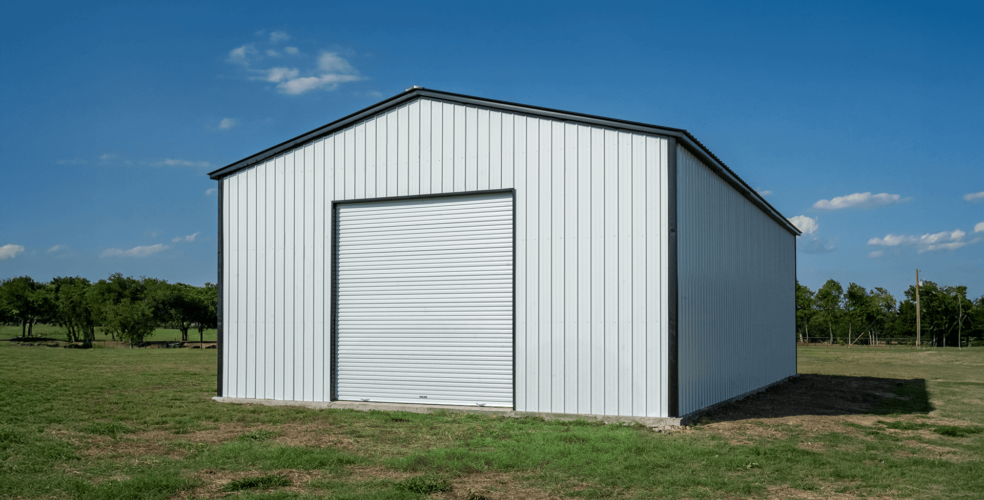 Steel metal building with vertical roof panels and a large roll-up garage door, designed for storage, workshops, or commercial use.