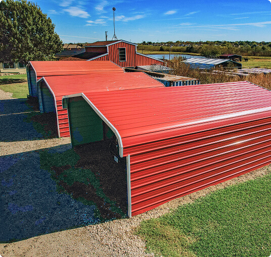 Three red metal carports in field
