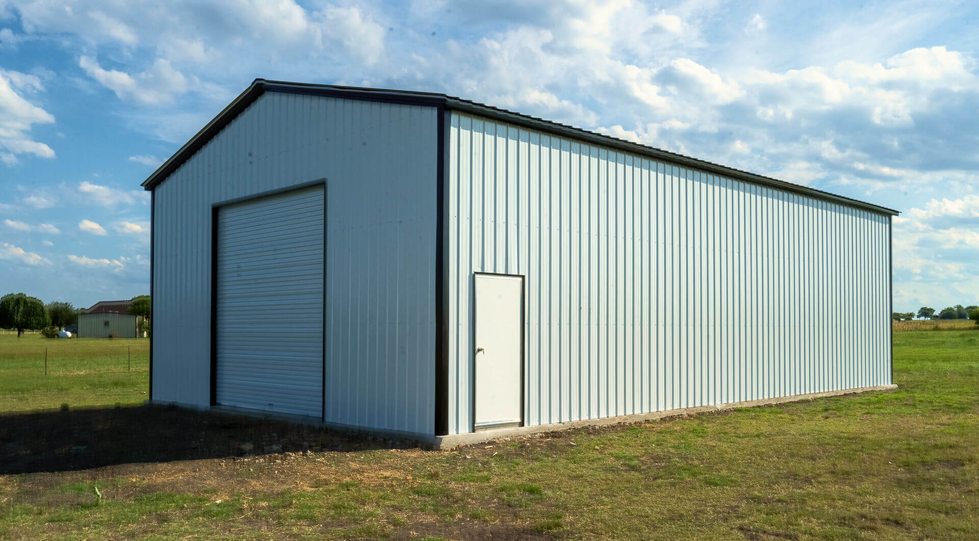 Black 30×50 metal garage with attached lean-to and roll-up doors, demonstrating a steel garage design with additional covered space for vehicles or equipment storage.