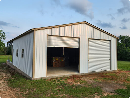 Spacious white steel garage with two roll-up doors, one open revealing storage boxes inside