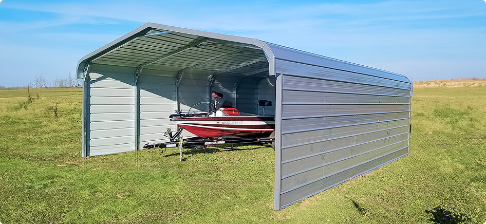 Enclosed metal carport with a red boat on a trailer stored inside, set on a green field