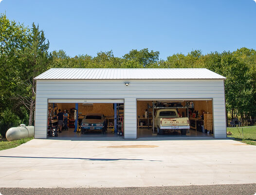 Spacious two-bay metal garage with vintage vehicles and workshop equipment inside