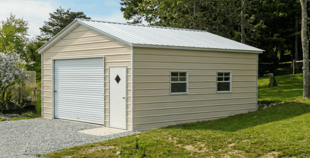 Beige metal garage with horizontal steel siding, white trim, roll-up garage door, entry door, and double side windows, installed on a gravel base in a landscaped backyard setting.