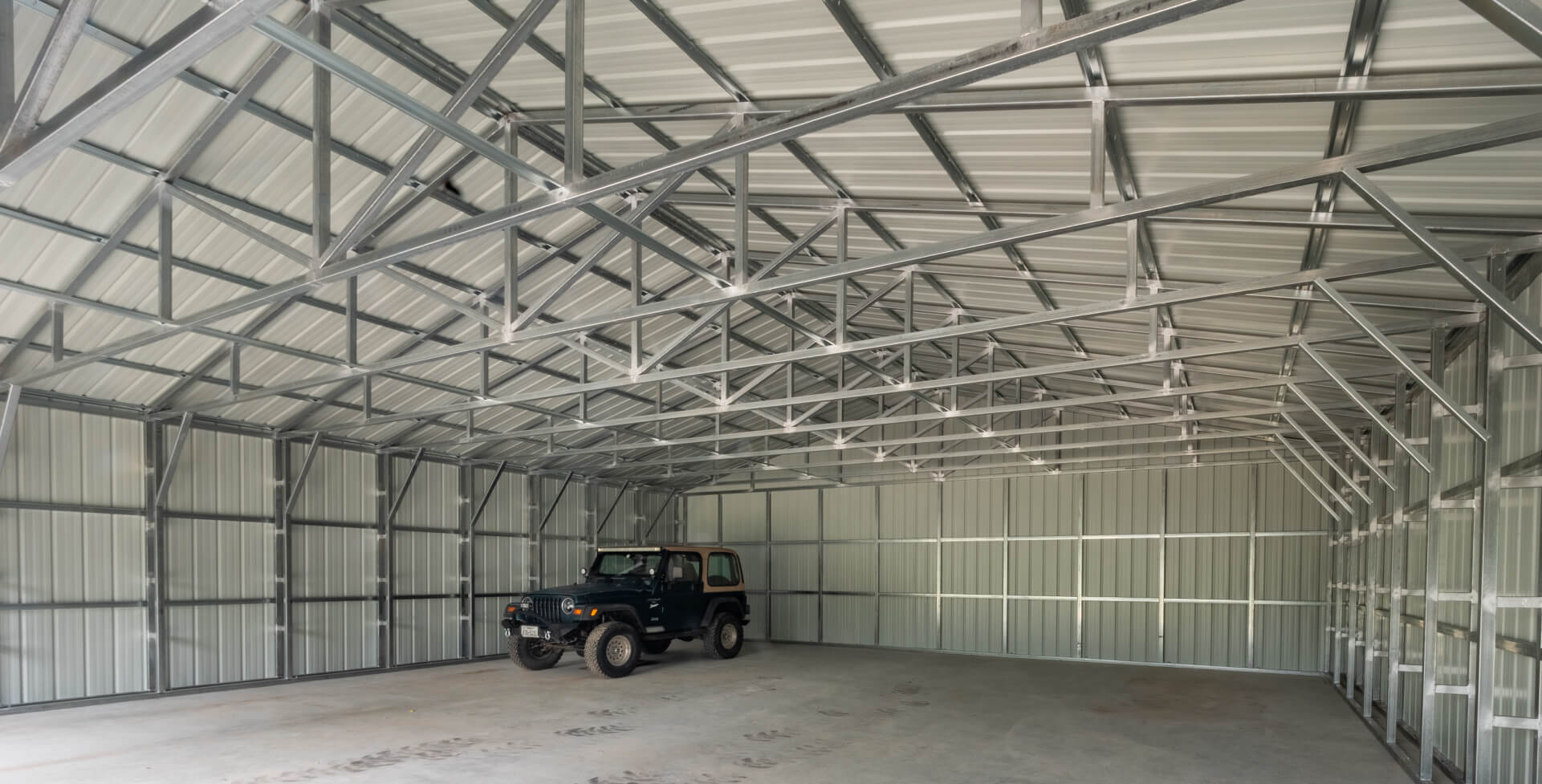 Interior view of galvanized steel truss roof system inside a prefabricated metal building, highlighting structural framing and corrugated metal roof panels.