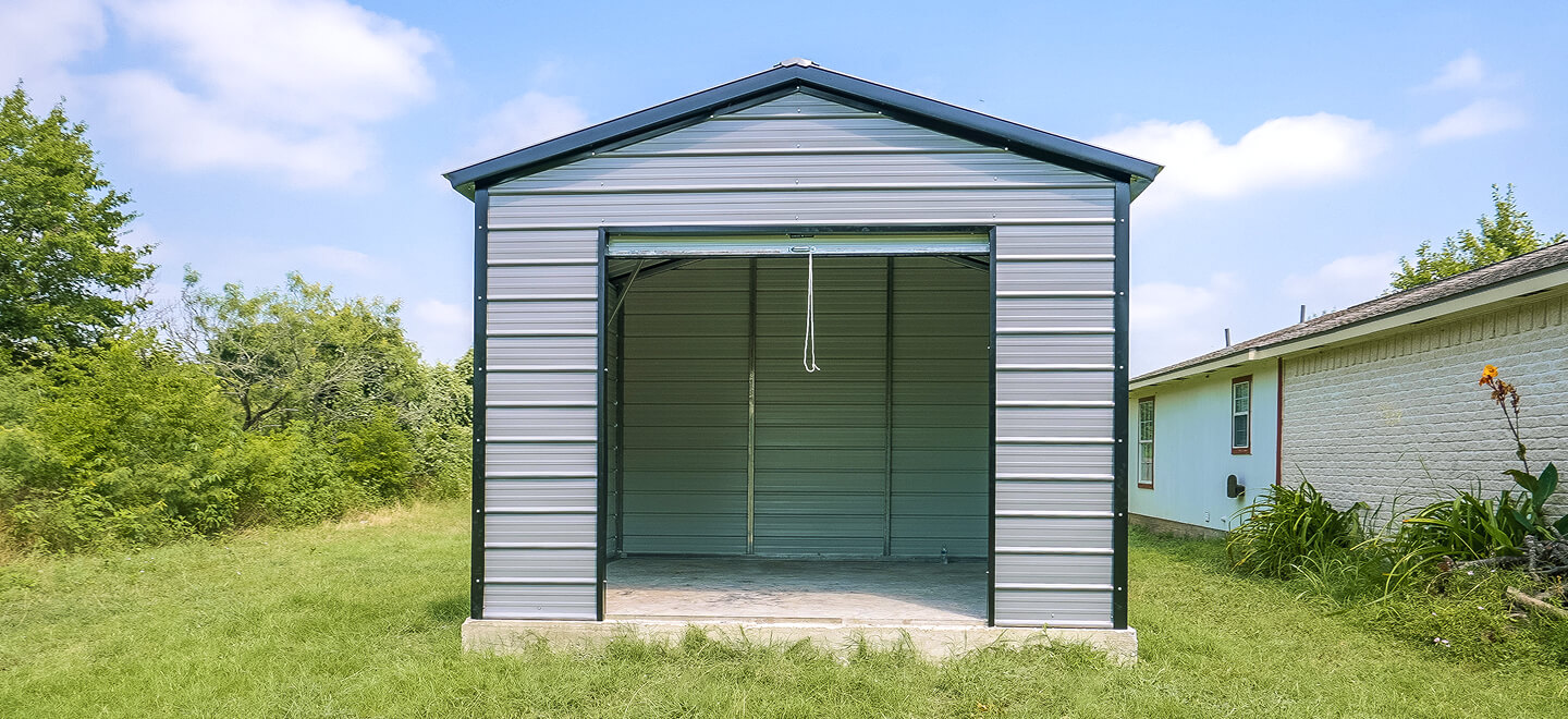 Small gray metal garage with an open roll-up door on a concrete pad in a residential backyard