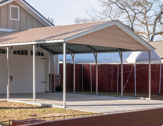 Freestanding mobile home carport next to a garage and driveway.