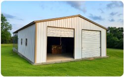 Large metal workshop and storage building with beige siding, two garage bays, and multiple side windows
